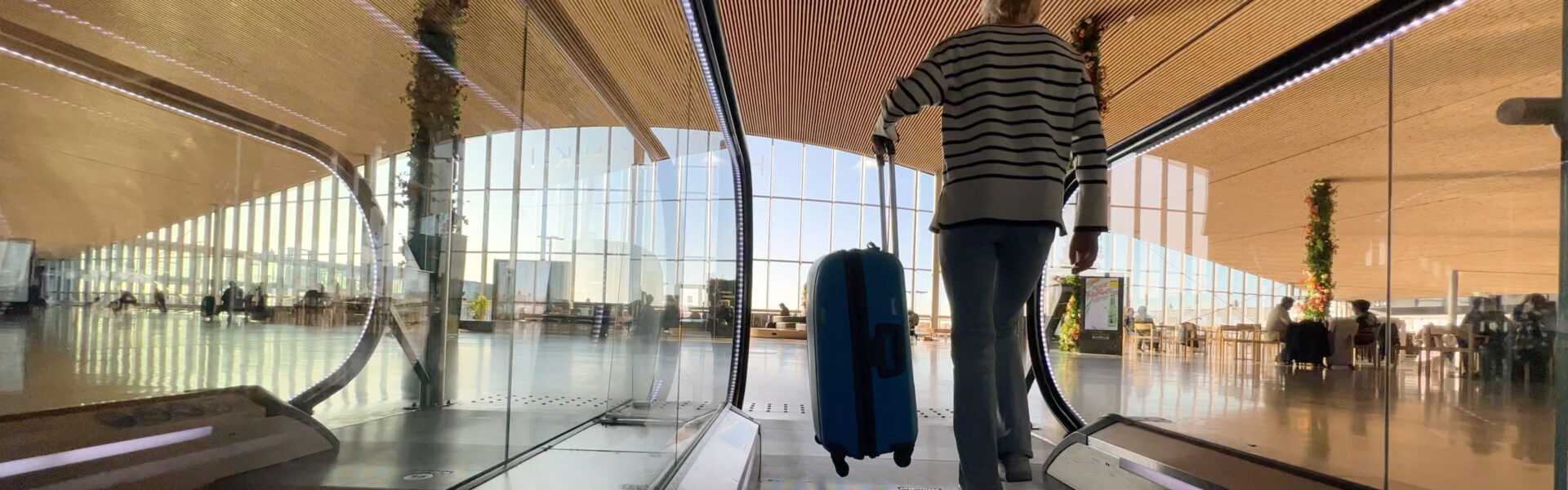 Young woman with a piece of luggage
entering a departure hall.